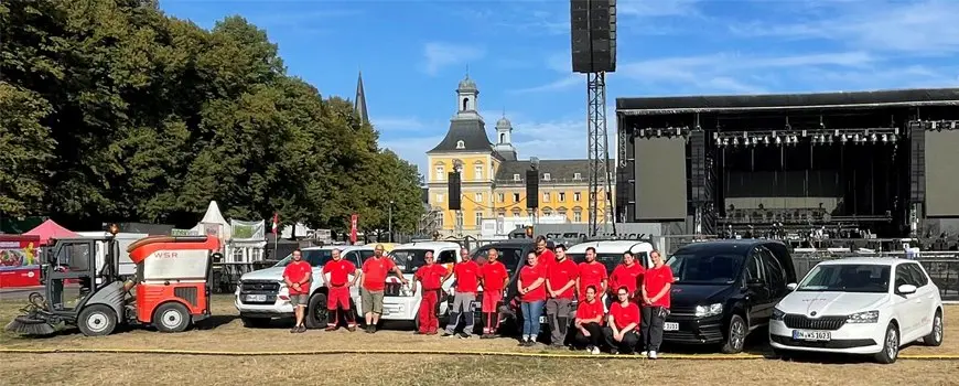 WSR-Team in roter Arbeitskleidung vor einer Konzertbühne im Bonner Hofgarten